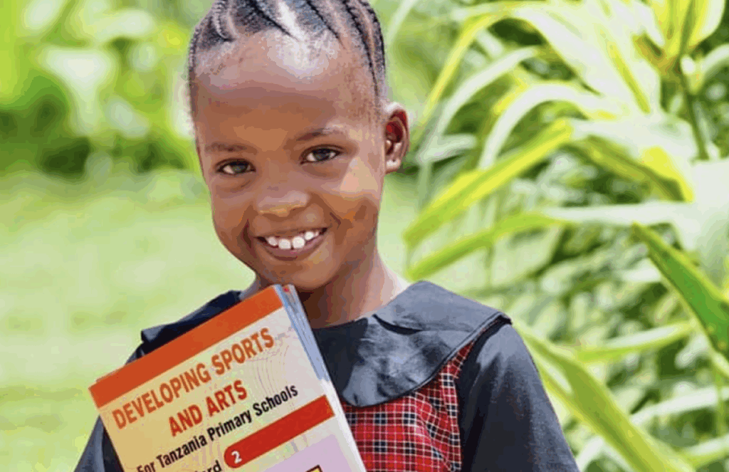 A young girl smiling and holding a book